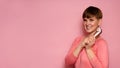 A studio shot of a young woman holding a vacuum vibrator in her hands. Bright pink background. The concept of female