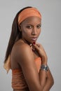 Studio shot of the young woman of the mulatta with make up with a terracotta bandage on the head on gray background