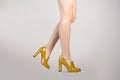 Studio shot of a young woman`s legs in a pair of yellow high heeled loafers on greynd Royalty Free Stock Photo