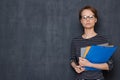 Portrait of serious focused young woman holding folders and pen Royalty Free Stock Photo