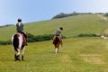 Studland, Dorset, UK - June 04 2018: Two women on horseback, walking along a coast path on a headland