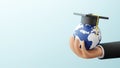 Study abroad concept design of business hand holding globe with graduation cap and plane Royalty Free Stock Photo