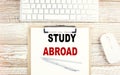 STUDY ABROAD text on clipboard on wooden background, business concept Royalty Free Stock Photo