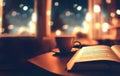 study book with coffee cup on cozy cafeteria at night first person view bokeh on background Royalty Free Stock Photo
