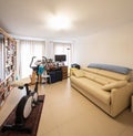 Study with an exercise bike in the middle of the room, leather sofa and bookshelf full of books Royalty Free Stock Photo