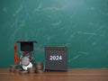Study goals, 2024 Desk calendar, Glass bottle with graduation hat and stack of coins. The concept of saving money for education, Royalty Free Stock Photo