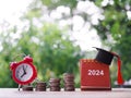 Study goals, 2024 Desk calendar with graduation hat and red alarm on stack of coins. Royalty Free Stock Photo