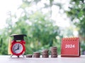 Study goals, 2024 Desk calendar, Red alarm with graduation hat and stack of coins. The concept of saving money for education, Royalty Free Stock Photo