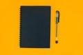 Study material containing a black paper diary and a black ball point pen placed on an orange background Royalty Free Stock Photo