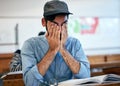 Studying all night has made him tired. an university student covering his face in exhaustion in class. Royalty Free Stock Photo