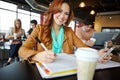 Studying during a coffee break. A beautiful young university student using her smartphone in a coffeee shop while Royalty Free Stock Photo