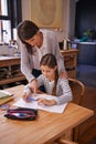 Studying, mother and daughter for writing with help, advice and check for homework with education. Mom, girl and