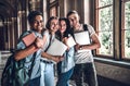 We studying together and friends forever!Four happy students holding books,laptops and smiling while looking at camera Royalty Free Stock Photo