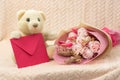 White teddy bear with flowers and envelope with congratulations.