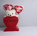 Stuffed bear in white, two balloons with the words `I love you` stuck in a red heart with the words `I love you` Royalty Free Stock Photo