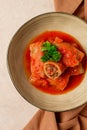 Stuffed cabbage rolls, with minced meat, in tomato sauce, on a beige background, top view, no people, selective focus.