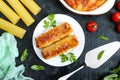 Stuffed cannelloni with bechamel sauce. Cannelloni pasta baked with meat, cream sauce, cheese on a black background. Top view, Royalty Free Stock Photo