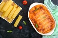 Stuffed cannelloni with bechamel sauce. Cannelloni pasta baked with meat, cream sauce, cheese on a black background. Top view, Royalty Free Stock Photo