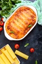 Stuffed cannelloni with bechamel sauce. Cannelloni pasta baked with meat, cream sauce, cheese on a black background. Top view, Royalty Free Stock Photo