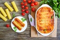 Stuffed cannelloni with bechamel sauce. Cannelloni pasta baked with meat, cream sauce, cheese on a wooden background. Top view, Royalty Free Stock Photo