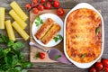 Stuffed cannelloni with bechamel sauce. Cannelloni pasta baked with meat, cream sauce, cheese on a wooden background. Top view, Royalty Free Stock Photo