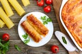 Stuffed cannelloni with bechamel sauce. Cannelloni pasta baked with meat, cream sauce, cheese on a wooden background. Top view, Royalty Free Stock Photo