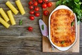 Stuffed cannelloni with bechamel sauce. Cannelloni pasta baked with meat, cream sauce, cheese on a wooden background. Top view, Royalty Free Stock Photo