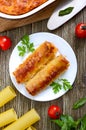 Stuffed cannelloni with bechamel sauce. Cannelloni pasta baked with meat, cream sauce, cheese on a wooden background. Top view, Royalty Free Stock Photo