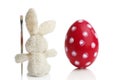 Stuffed Easter bunny paints a red Easter egg