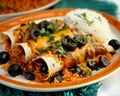 Stuffed enchiladas with rice and black olives on a plate, mexican dishes picture