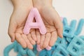 Stuffed felt letter of the alphabet in open hands of child.