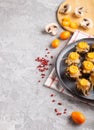 Stuffed fried champignons with cheese, kumquats and green peas on a gray concrete background. side view, copy space Royalty Free Stock Photo