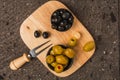 Stuffed green and black olives on a fruit chopping board on a stone background. 2