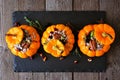 Stuffed fall mini pumpkins with rice, cranberries, cabbage and nuts on a serving board over dark wood