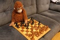 A stuffed monkey is playing a game of chess on a wooden board Royalty Free Stock Photo
