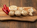 Stuffed mushrooms cups and chilly peppers and garlic cloves on a wooden board and table. High quality product with breadcrumbs, Royalty Free Stock Photo