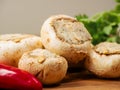 Stuffed mushrooms cups and chilly peppers and garlic cloves on a wooden board and table. High quality product with breadcrumbs, Royalty Free Stock Photo