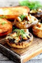 Stuffed mushrooms and fried toasts on a chopping board and wooden table. Baked mushroom caps stuffed with cheese and meat recipe