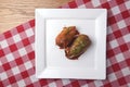 Stuffed paprika pepper with meat, rice and vegetables. Served on a white square plate over red plaid tablecloth Royalty Free Stock Photo