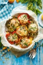 Stuffed peppers, halves of peppers stuffed with bulgur, dried tomatoes, herbs and cheese in a baking dish on a blue wooden table,