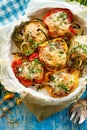 Stuffed peppers, halves of peppers stuffed with bulgur, dried tomatoes, herbs and cheese in a baking dish on a blue wooden table,