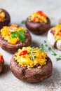 Stuffed portobello mushrooms with bulgur, vegetables and aromatic herbs on concrete background. Vegetarian food. Close up