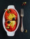 Stuffed red sweet peppers with feta cheese and olives in baking dish on black stone background, top view Royalty Free Stock Photo