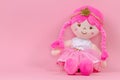 Stuffed soft doll sitting on pink background