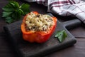 Stuffed sweet peppers with rice mushrooms and cheese with herbs. Baked halves of red peppers with filling. Dark wooden background Royalty Free Stock Photo