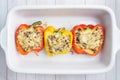 Stuffed sweet peppers with rice mushrooms and cheese with herbs. Baked halves of red and yellow peppers with filling Royalty Free Stock Photo