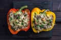 Stuffed sweet peppers with rice mushrooms and cheese with herbs. Baked halves of red and yellow peppers with filling Royalty Free Stock Photo