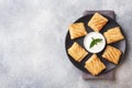 Stuffed thin pancakes rolled into rolls are grilled on a black plate. Cream sauce with mint leaves. Copy space