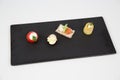 Stuffed tomato and a selection of delicious seafood dish with vegetables on a black tray