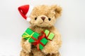 A stuffed toy Teddy bear in a red Santa Claus hat with a pompom on one ear, holding green gift boxes in its paws. White background Royalty Free Stock Photo